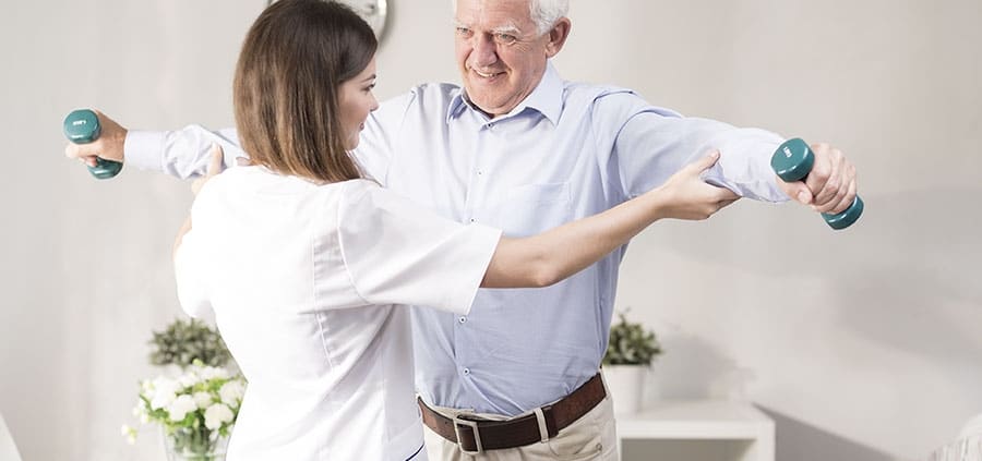 Physical Therapist working with patient holding weights