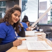 Nursing student sitting in classroom over books, looking at the camera smiling