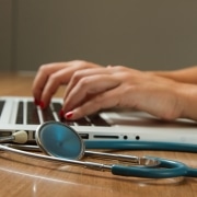 Woman with a stethoscope typing on a laptop