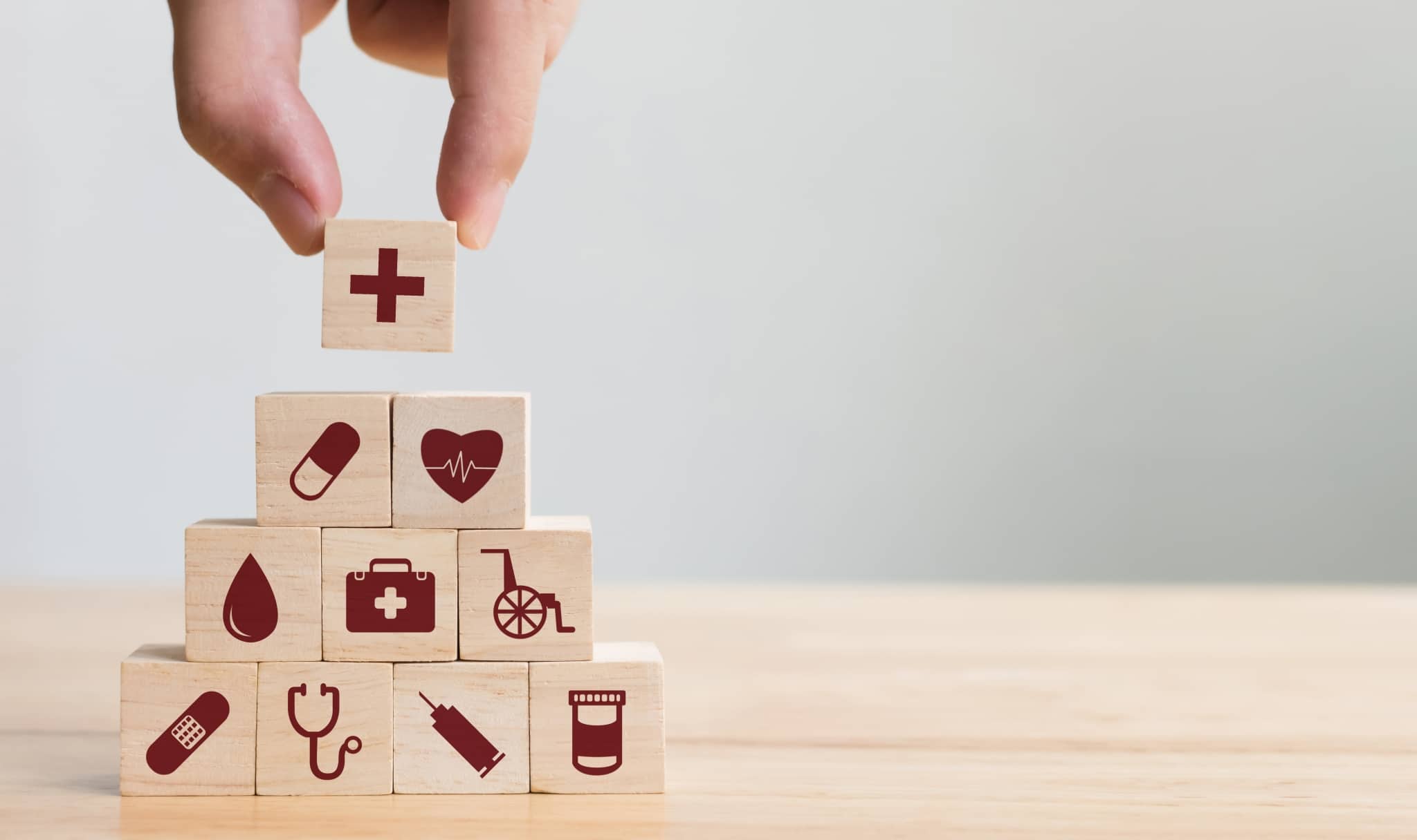 Hand arranging blocks of wood with medical icons