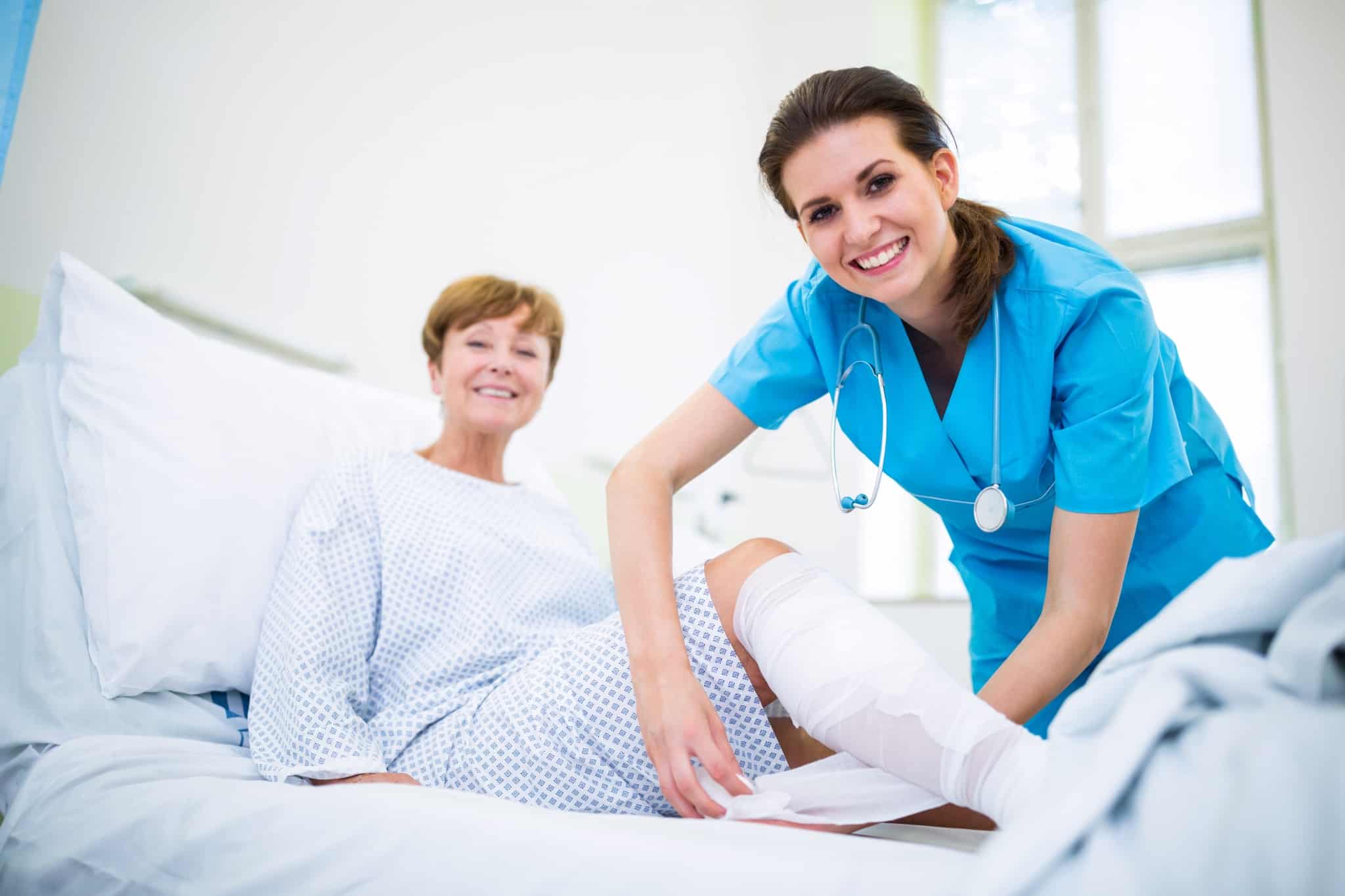 Smiling healthcare professional bandaging a patient's leg