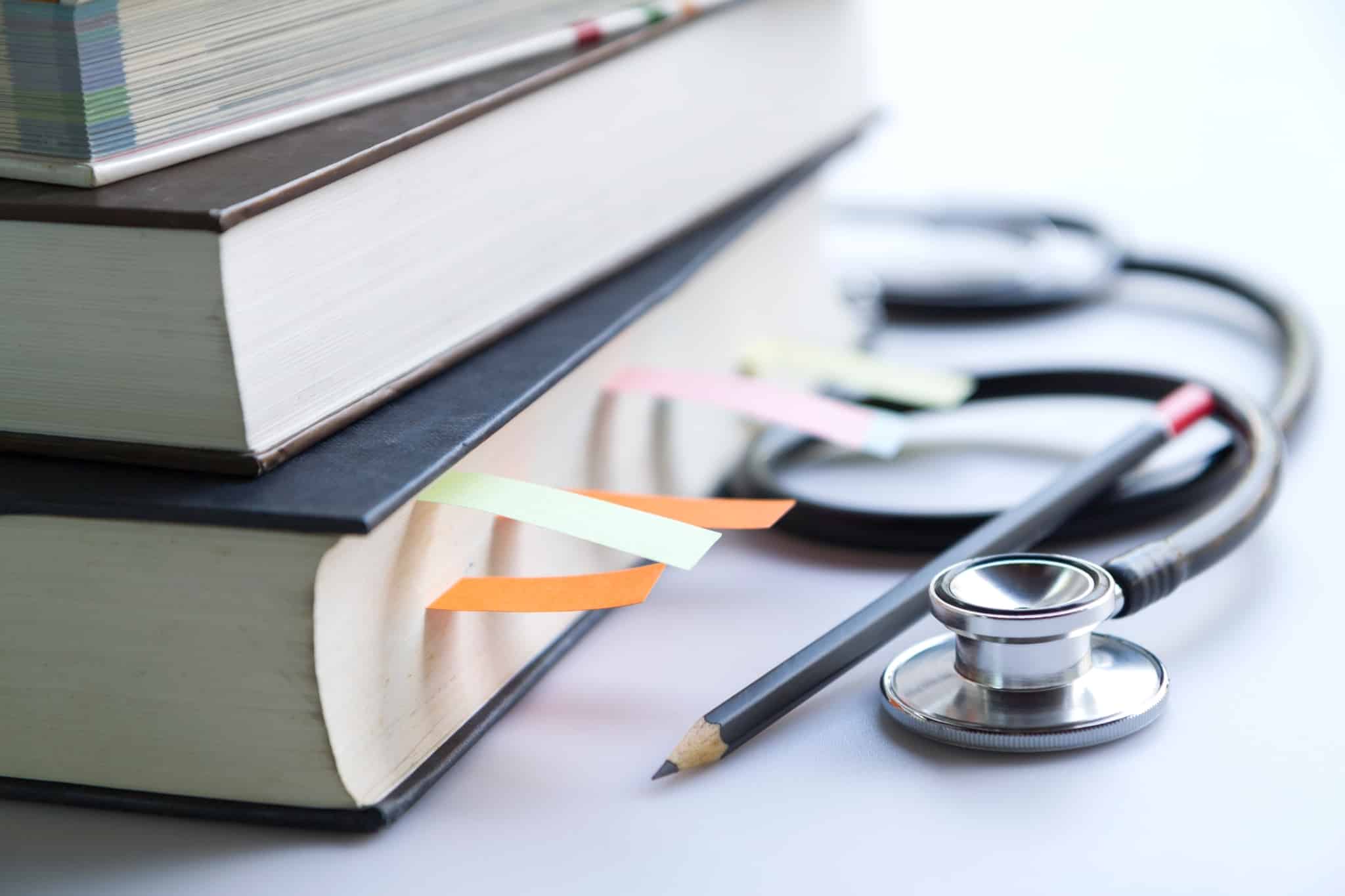 Stethoscope next to a stack of textbooks