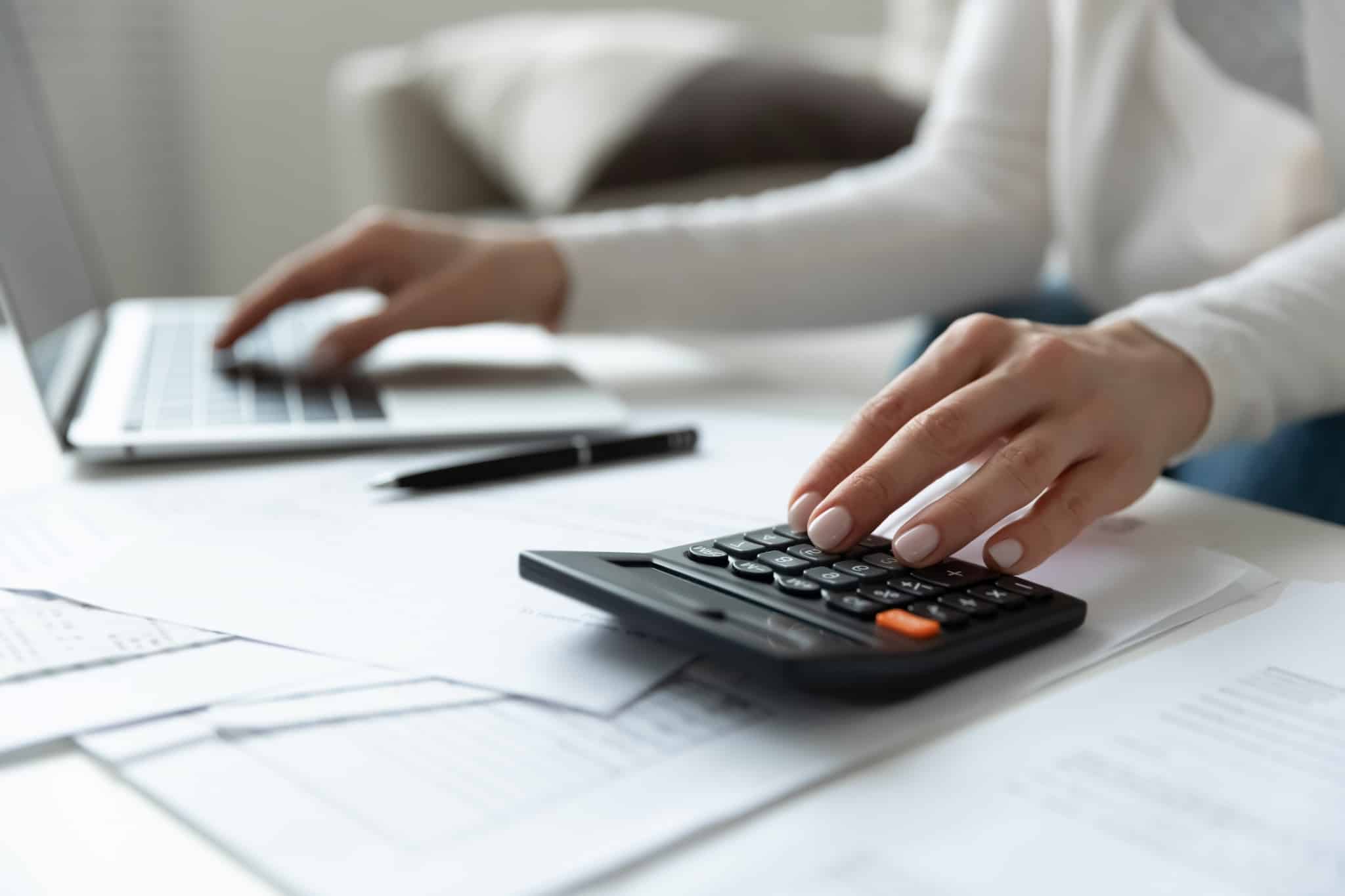 Close up of woman using a calculator and laptop
