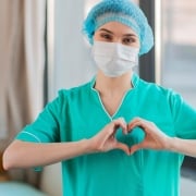 Masked nurse forming a heart with her hands