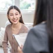 Smiling young woman on a couch next to a medical professional