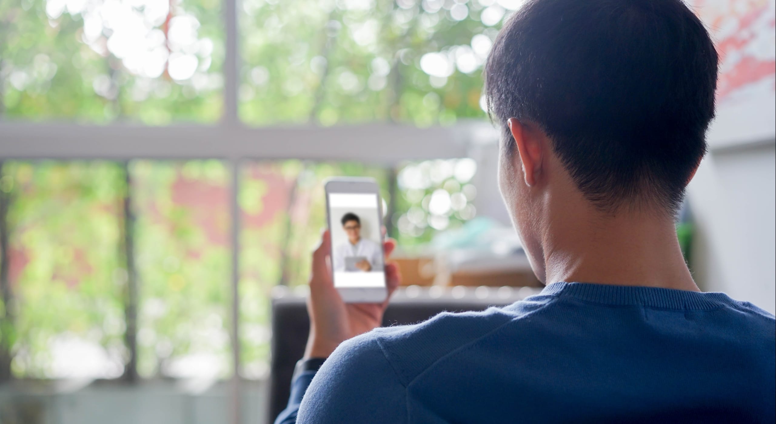 Asian man communicating with a doctor in a telehealth appointment
