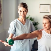 Physical Therapist Assistant helping a female patient lift weights