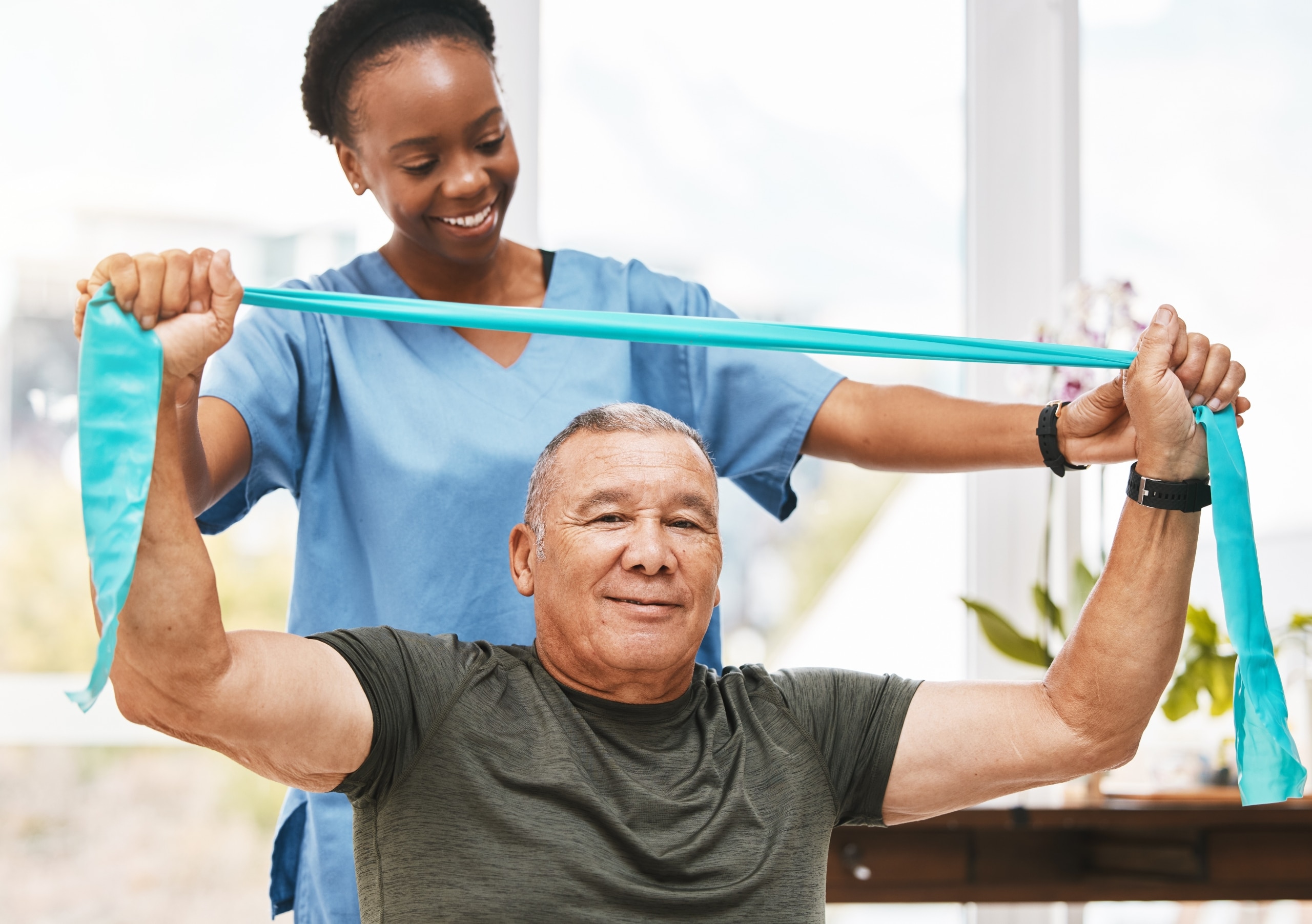 Physical Therapist Assistant helping an older man use exercise bands