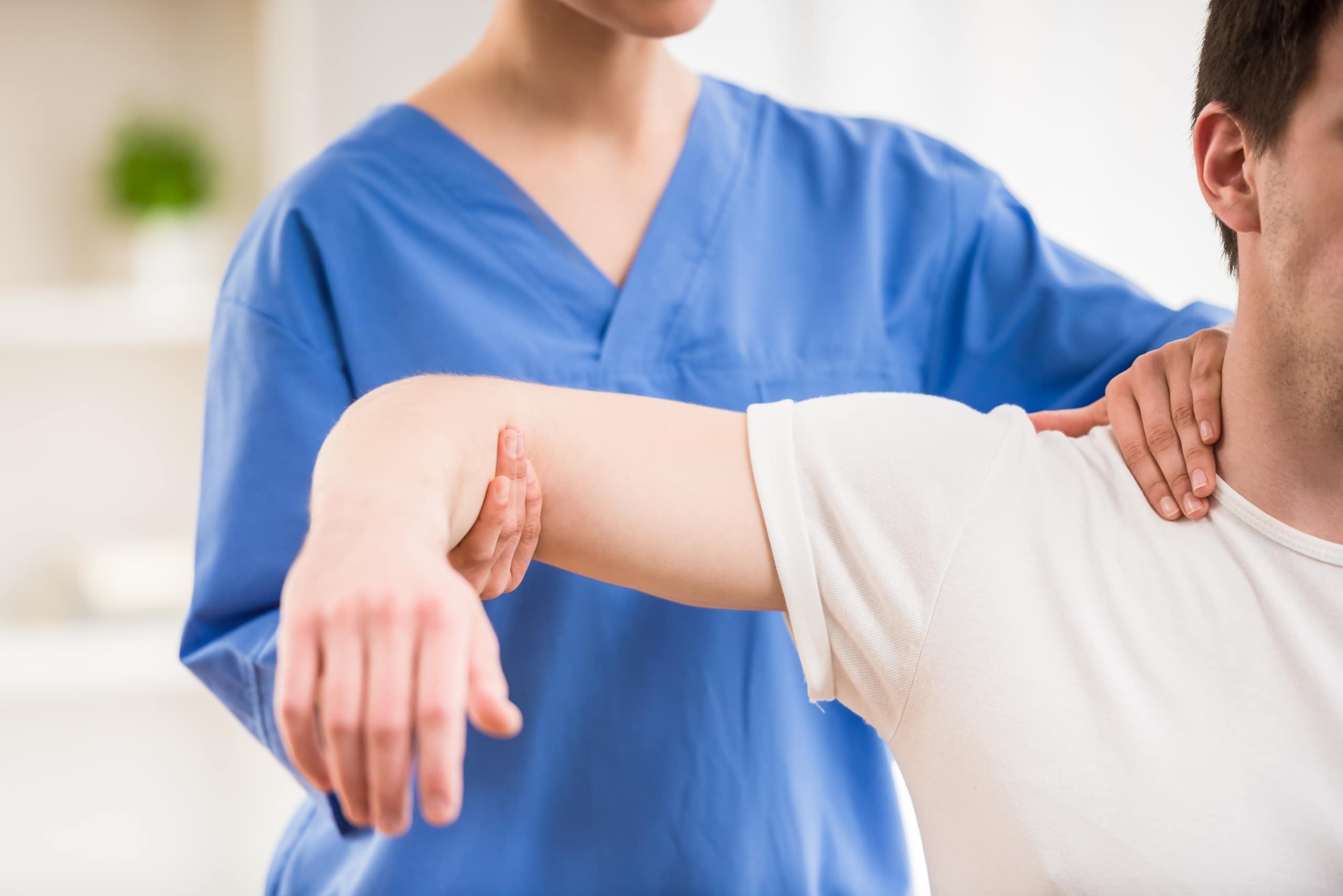 Physical therapy professional manipulating a man's arm and shoulder