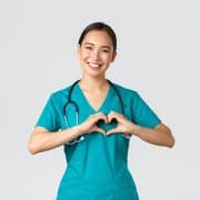 Smiling Asian nurse forming a heart with her hands
