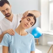 Physical therapy professional manipulating a woman's neck and shoulders