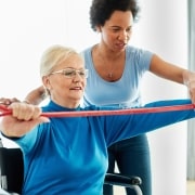 African-American medical professional helping a woman use an exercise band