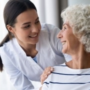 Elderly woman smiling at a young nurse over her shoulder