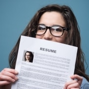 Woman with glasses holding up her resume