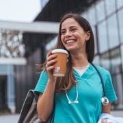 Smiling nurse holding a cup of coffee outside