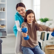Physical therapy professional helping a young girl lift weights