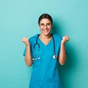 Smiling nurse holding her fists up against a solid backdrop