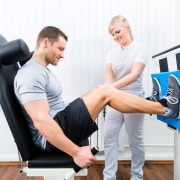 Physical therapy professional helping a male athlete use equipment