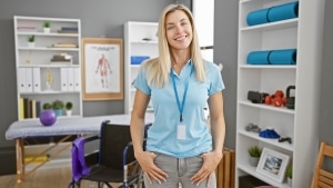 Smiling physical therapist assistant standing in a clinic