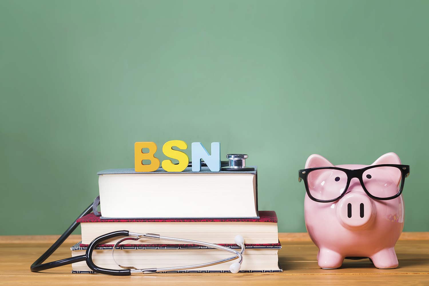 Stack of textbooks with a stethoscope and letter blocks that spell BSN